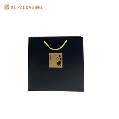 Logo personnalisé Sac de papier noir mat avec autocollants de calligraphie Kraft et poignées de cordon doré tordu pour emballage cadeau écologique